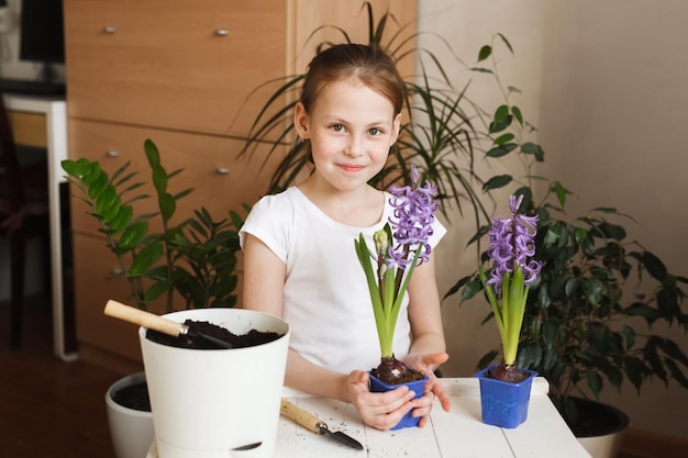 Cute kid girl replanting plants in real home interior