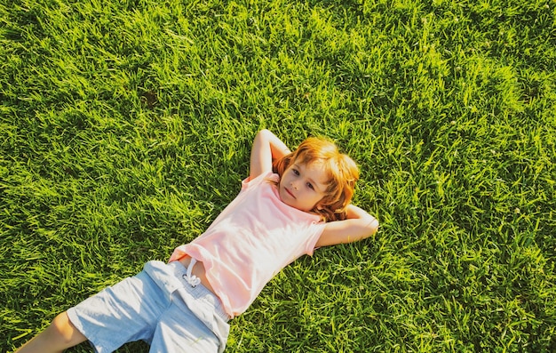 Cute kid lying on grass background happy carefree child boy enjoying on field and dreaming unity wit