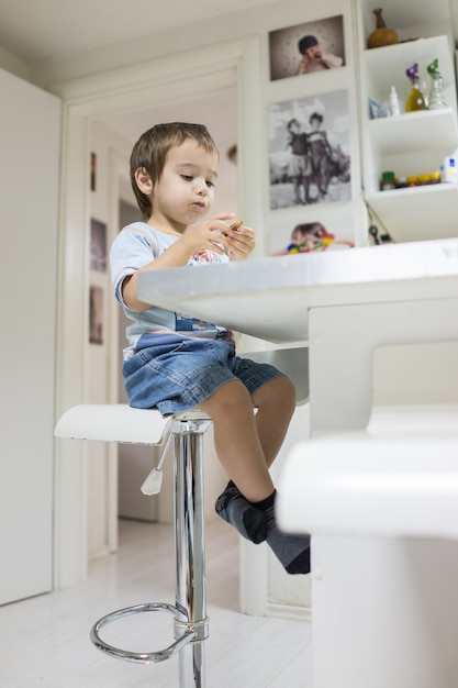 Cute kid sitting at home in the kitchen