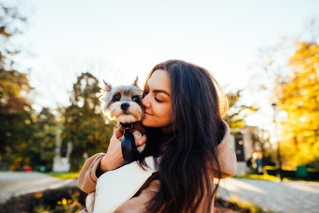 cute lady cuddling with a dog in the park on a background of autumn trees with yellow leaves