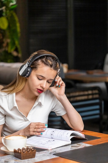 Cute lady wears headphones and reading book at the restaurant