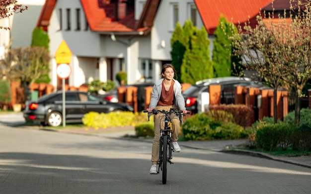 Cute laughing girl riding a bike in the evening in a calm city back view ecofriendly urban transport