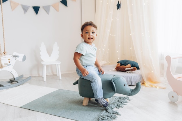 A cute little african american boy sits on a highchair in the shape of an elephantchildrens room design