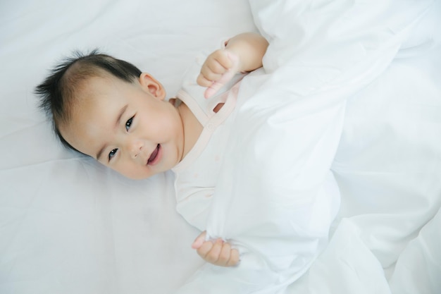 Cute little asian baby on bed with soft blanket indoors