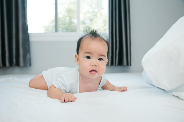 Cute little asian baby on bed with soft blanket indoors