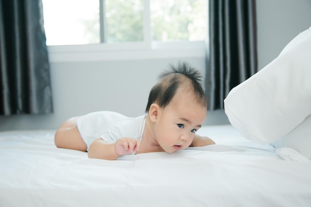 Cute little asian baby on bed with soft blanket indoors