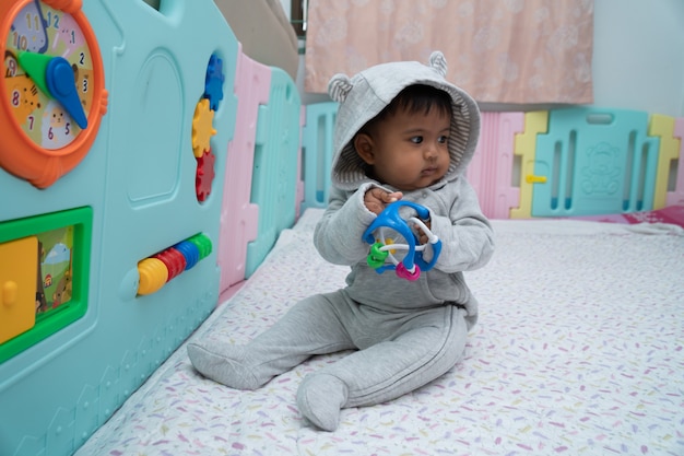 Cute little asin baby boy sitting and play toy in room