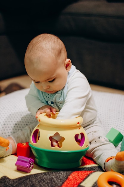 Cute little baby boy playing sorter toy sitting on the floor at home