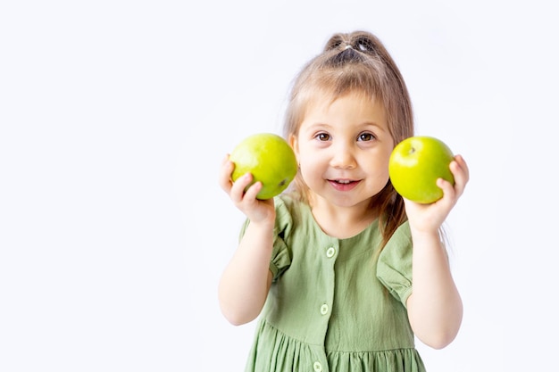 A cute little baby girl is holding a big green apple in her hands White isolated background Healthy foods for children or a healthy snack Space for text Highquality photography