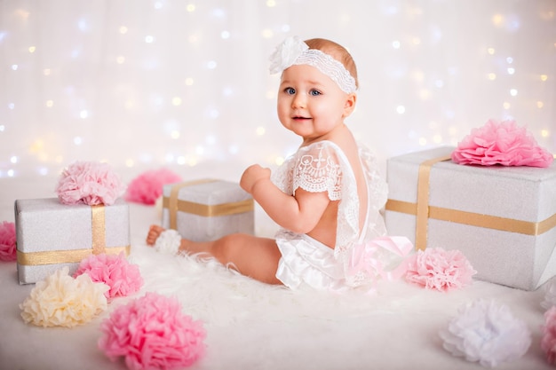 Cute little baby girl sitting among a lot of gift boxes celebrating birthday or christmas