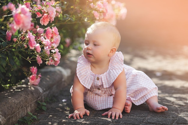 Cute little baby outdoors Lovely little girl with roses pretty child in the garden