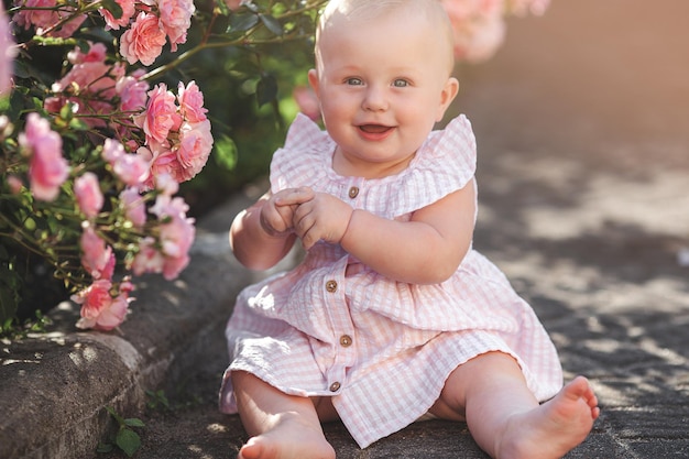 Cute little baby outdoors Lovely little girl with roses pretty child in the garden