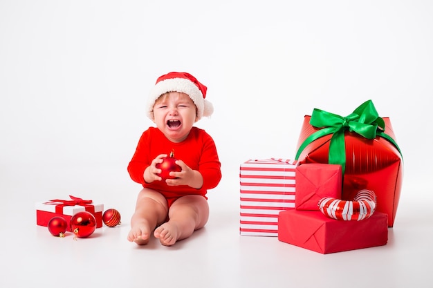 Cute little baby in a Santa costume with gifts