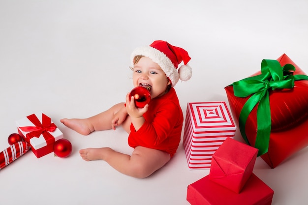 Cute little baby in a Santa costume with gifts