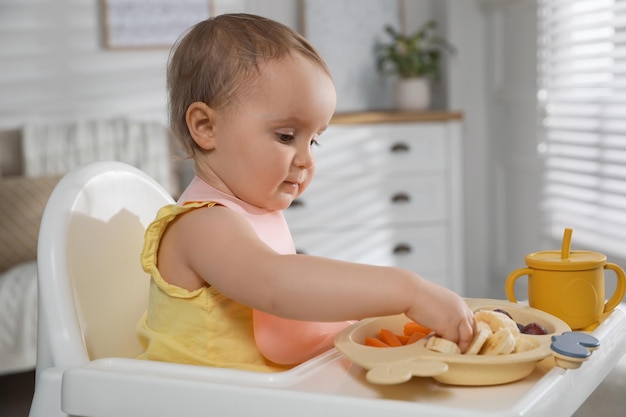 Cute little baby wearing bib while eating at home