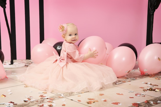 Cute little birthday girl playing with balloons at party