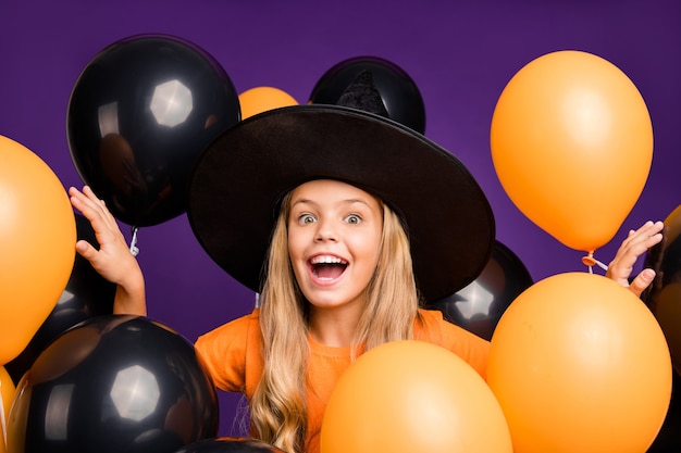 Cute little blonde girl with a witch hat and balloons