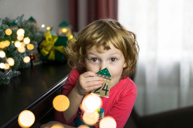 Cute little blonde with the number 24 advent calendar. Christmas traditions on Christmas Eve.