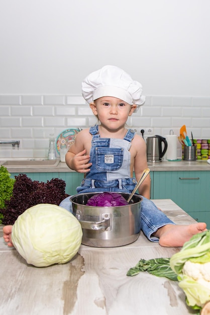 A cute little boy in a chefs costume cooks food with emotions