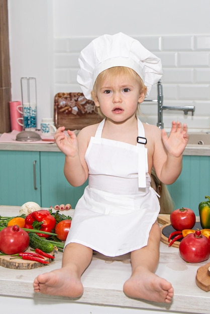 A cute little boy in a chefs costume cooks food with emotions