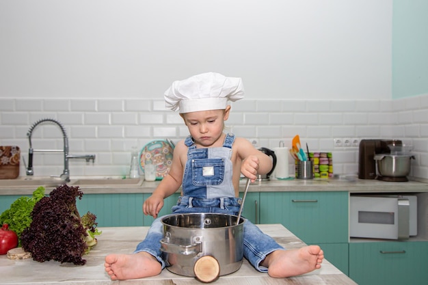 A cute little boy in a chefs costume cooks food with emotions