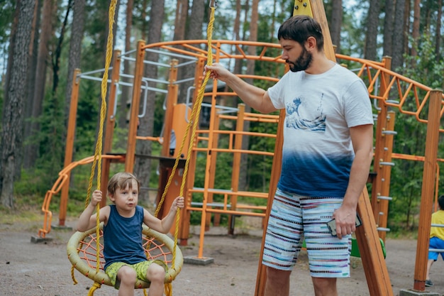 Cute little boy having fun on a swing at playground