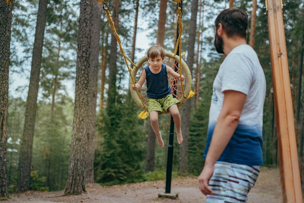 Cute little boy having fun on a swing at playground