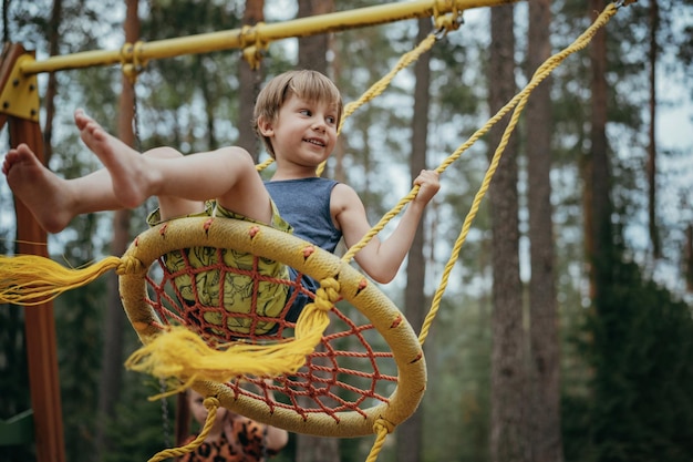 Cute little boy having fun on a swing at playground