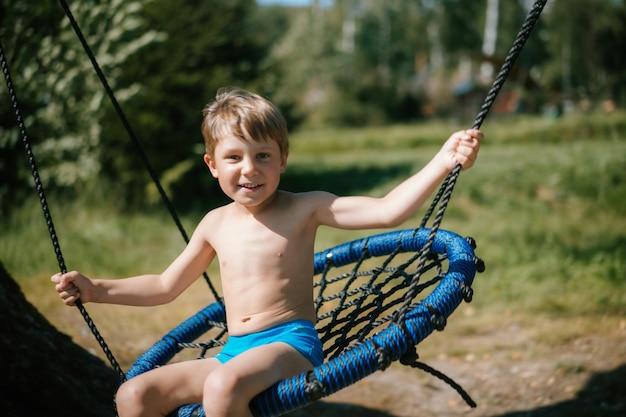 Cute little boy having fun on a swing at playground