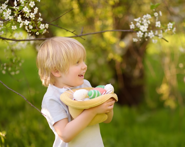 Cute little boy hunts for easter egg in spring park.