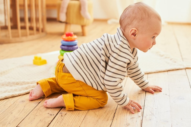 A cute little boy is crawling on the floor in his room