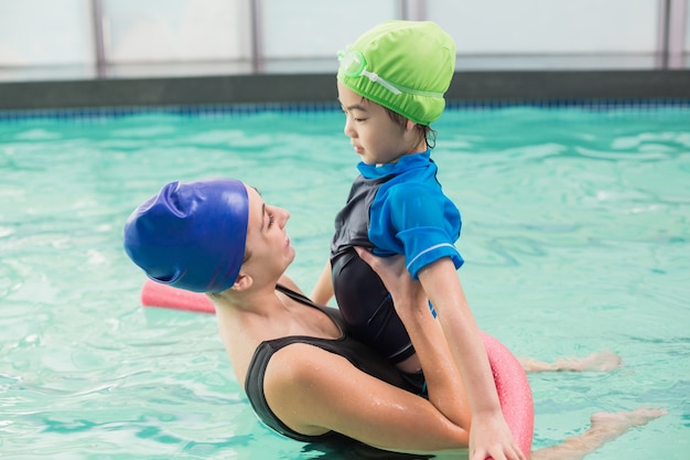 Cute little boy learning to swim with coach