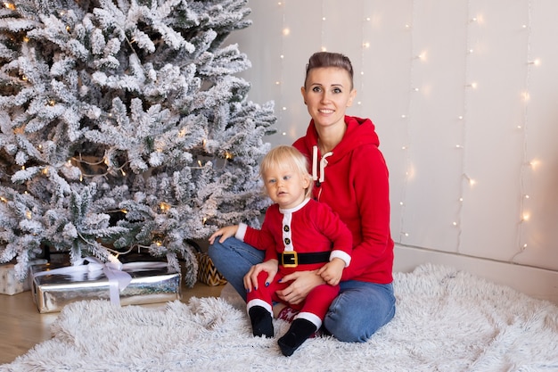 Cute little boy and mother near Christmas tree. Christmas, holidays and childhood concept.