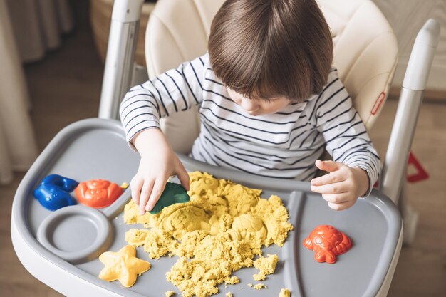 Cute little boy playing with kinetic sand Development of fine motor skills Early sensory education Activities Montessori Sensory plays at home