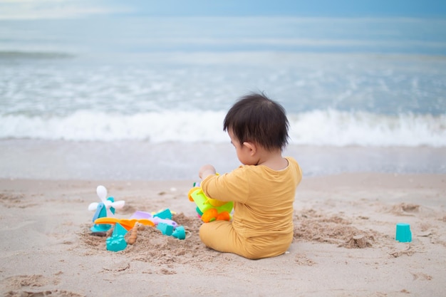 Cute little boy playing with sand on tropical beach