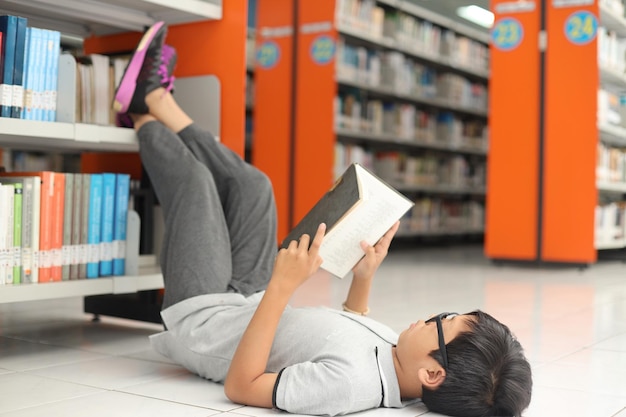 Cute little boy reading book in the library