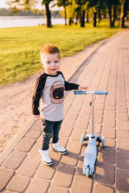 Cute little boy riding a kick scooter. Healthy outdoor activity