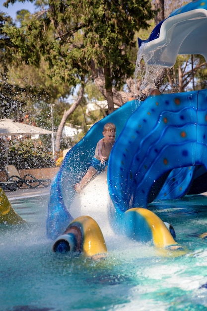 Cute little boy rolls down a water slide in a aquapark Concept summer vacation rest fun