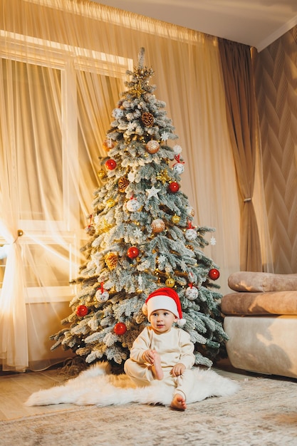 Cute little boy in santa hat with christmas tree Children's New Year Christmas tree Christmas atmosphere at home