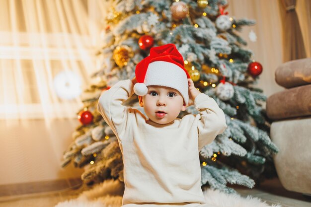 Cute little boy in santa hat with christmas tree Children's New Year Christmas tree Christmas atmosphere at home