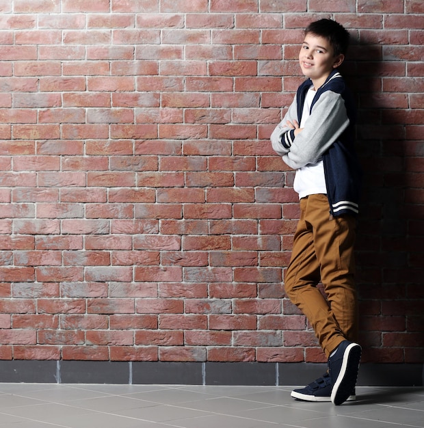 Cute little boy standing near brick wall