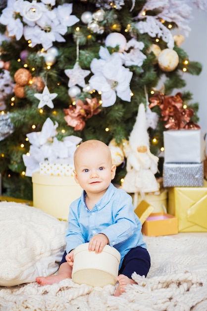 Cute little boy in a studio Child sitting by the christmas gifts