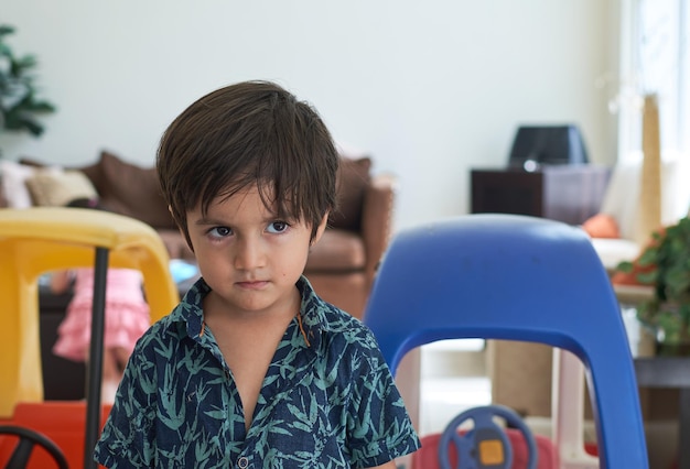 Cute little boy with an angry face on the background of colorful toy cars