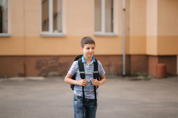 Cute little boy with backpack go home after scholl class