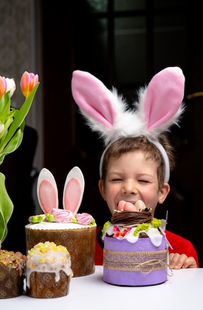 Cute little boy with bunny ears looking at tasty easter sweet cake