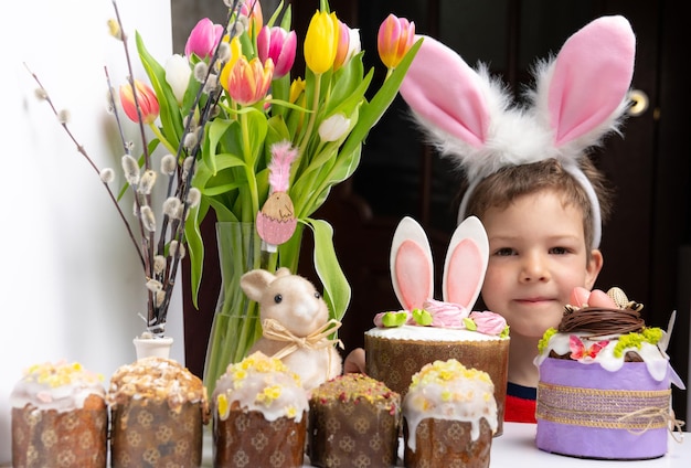 Cute little boy with bunny ears looking at tasty easter sweet cake