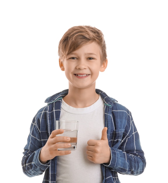 Cute little boy with glass of water showing thumb-up on white