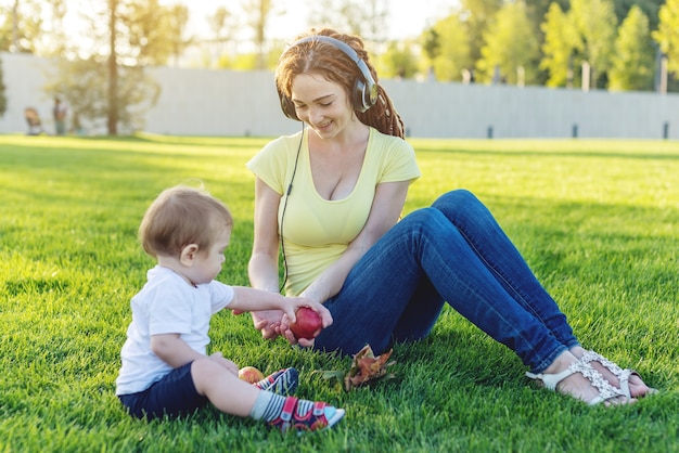 Cute little boy with her mother playing with apples