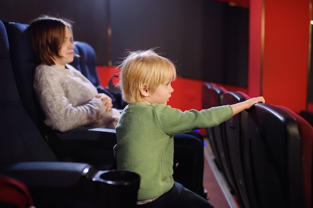 Cute little boy with his mother watching cartoon movie in the cinema