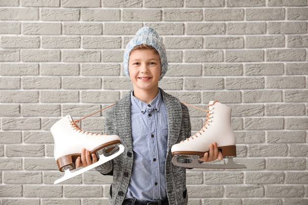 Cute little boy with ice skates against brick